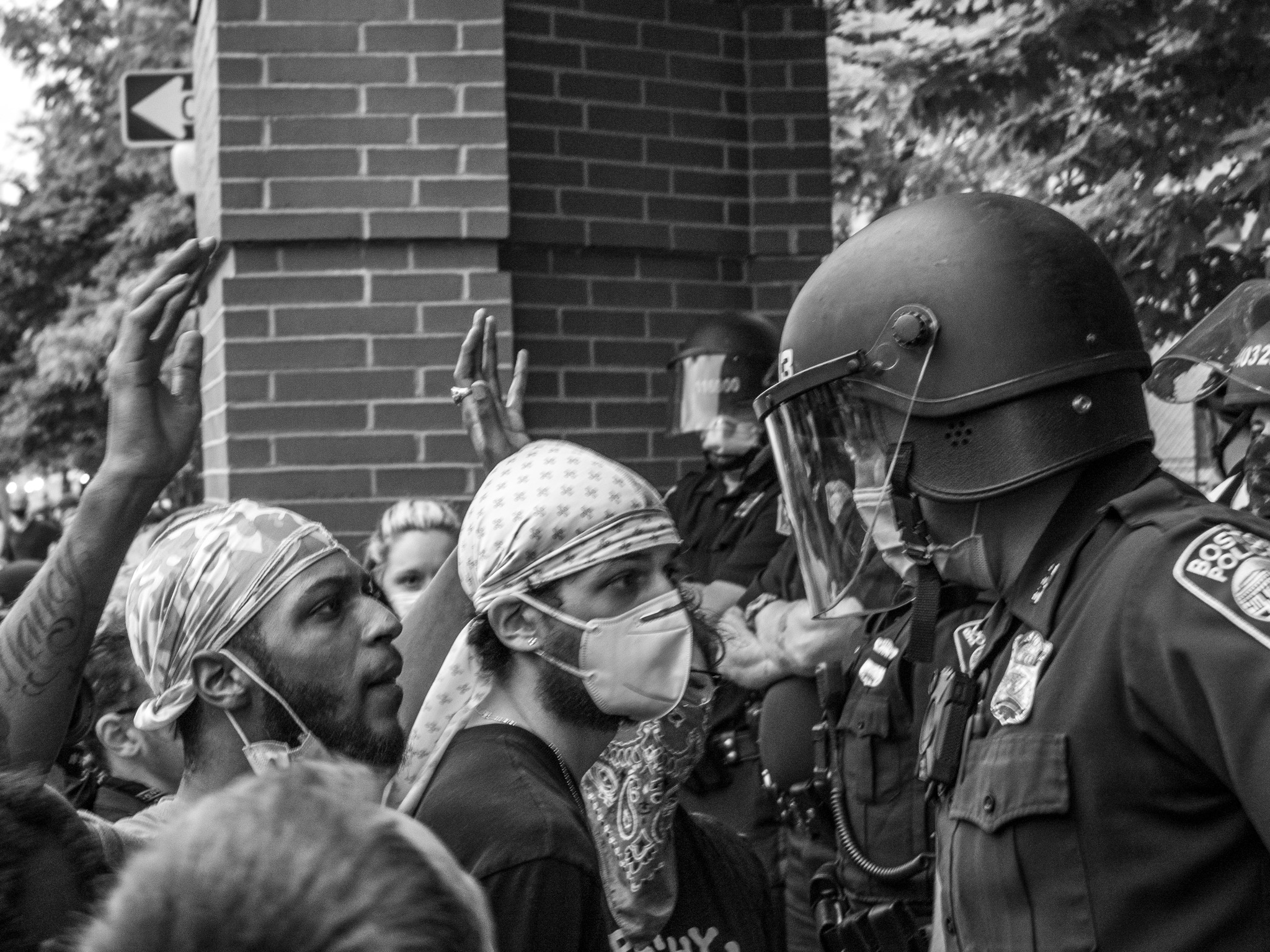 Protesters with hands raised facing riot police