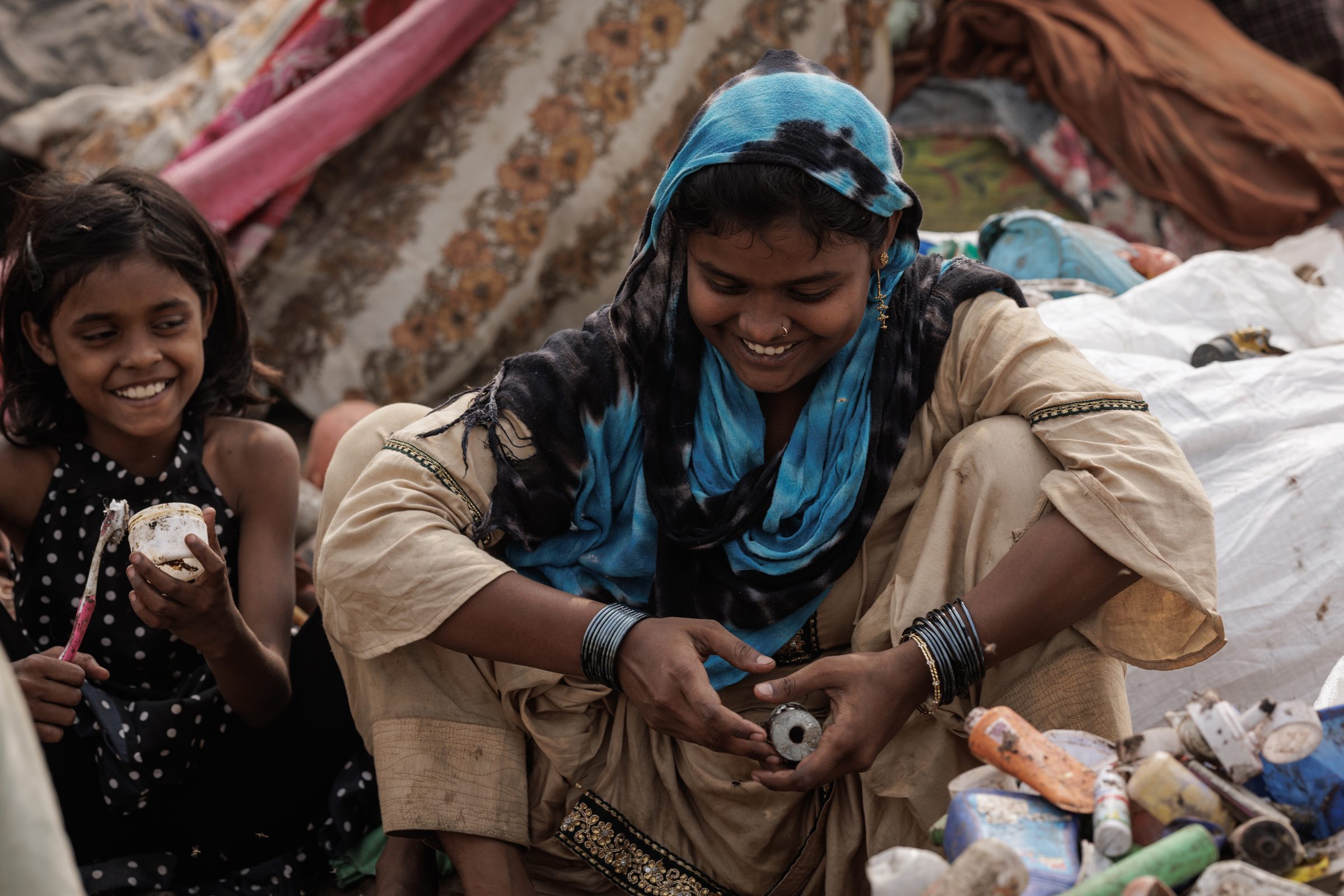Woman and girl smiling among collected waste in the colony