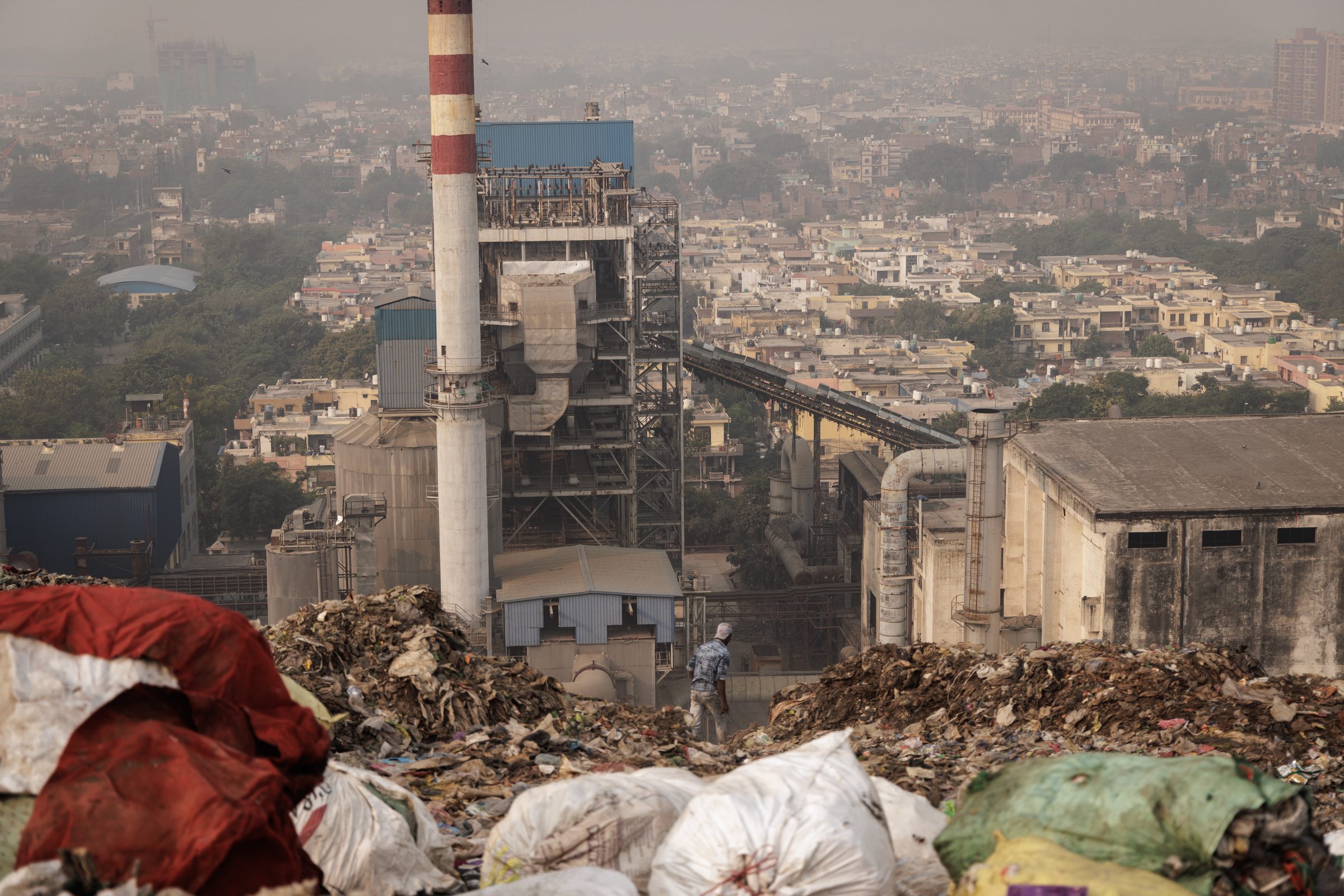View from the summit of Ghazipur landfill — waste plant smokestack, Delhi skyline in haze
