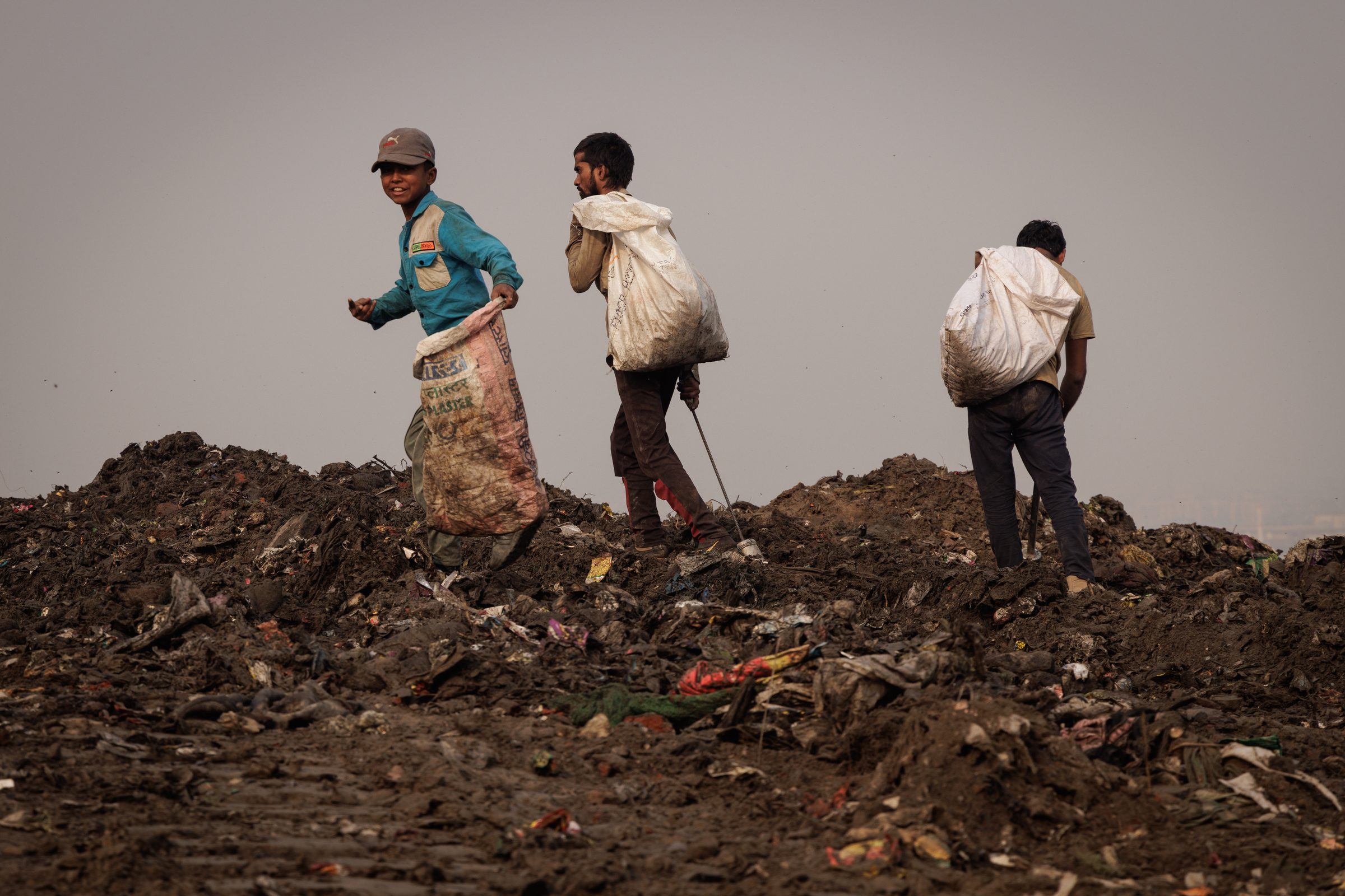 Three boys carrying full sacks across the ridge