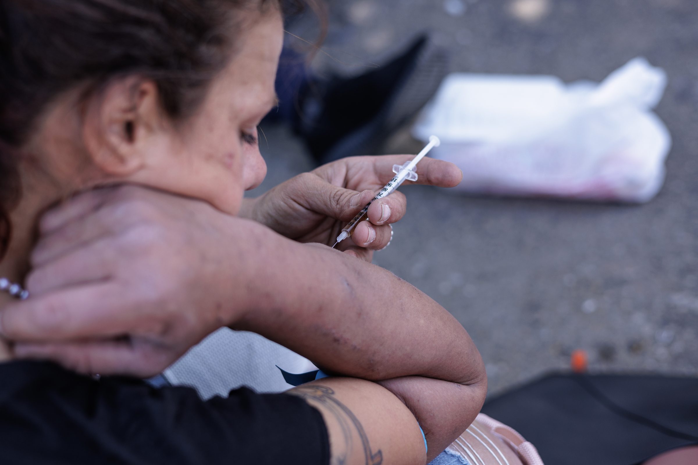 Woman preparing a syringe on the street