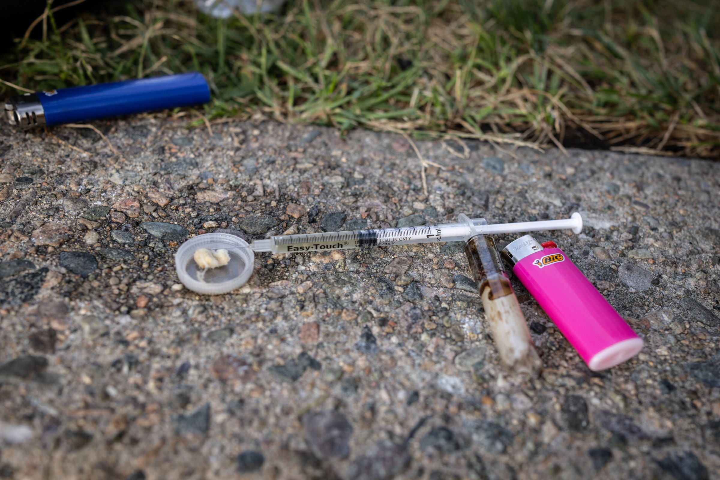 A syringe, cooker, and two lighters left on the pavement at Mass and Cass