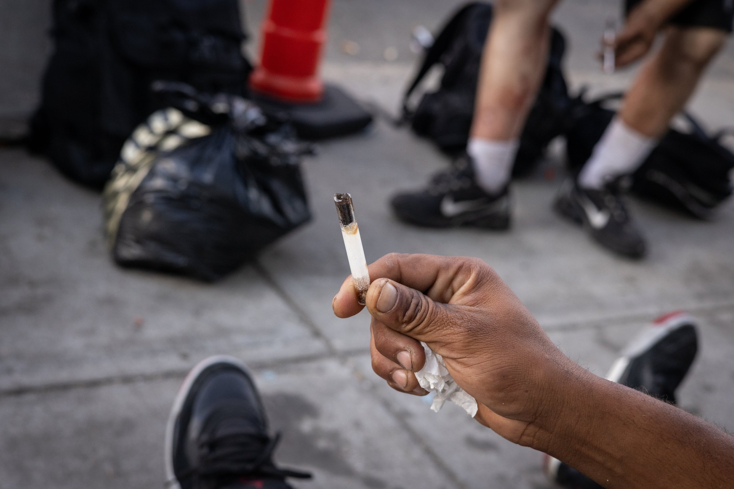 A man's hand holds a glass stem on the sidewalk at Mass and Cass
