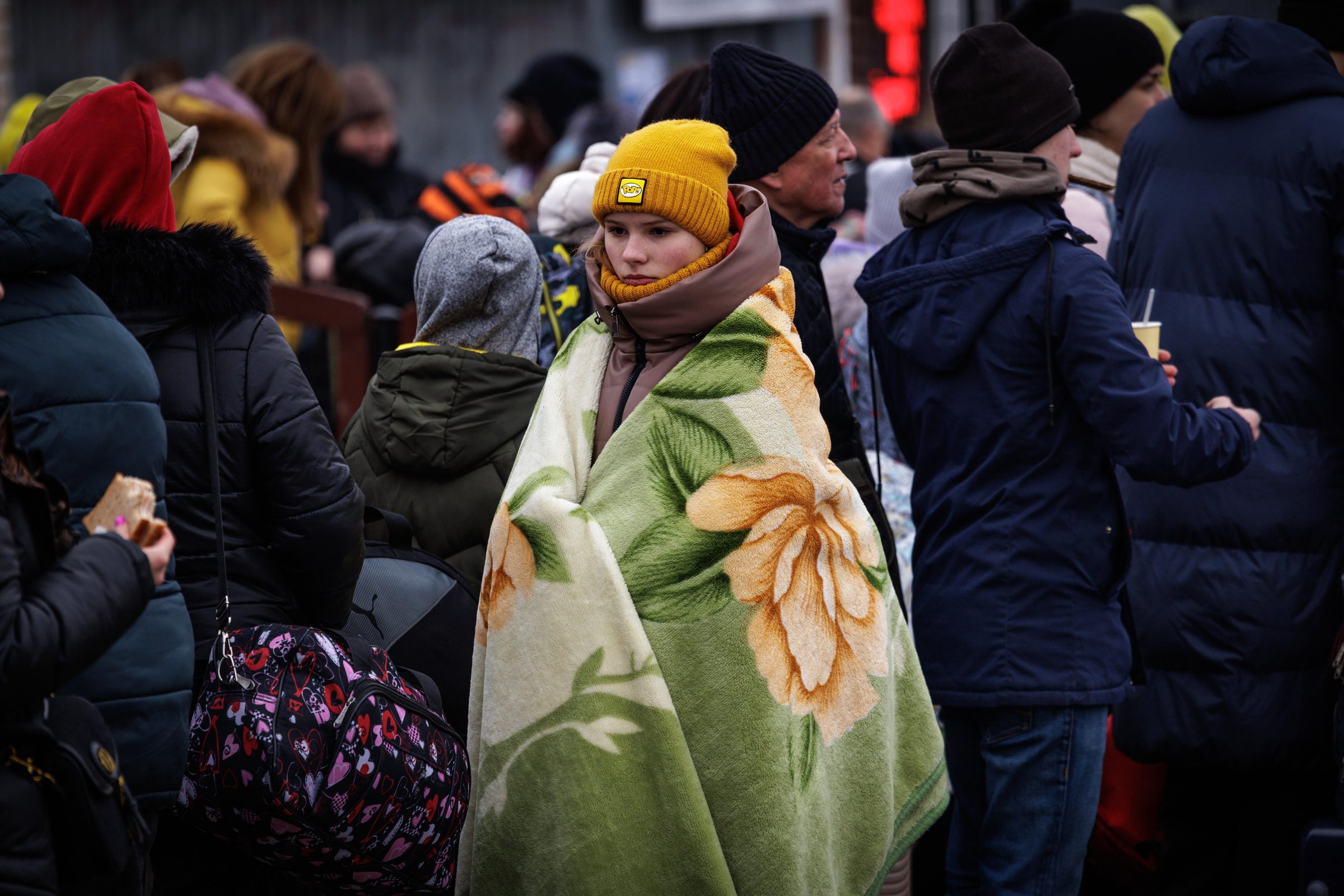 Young woman wrapped in floral blanket among the crowd